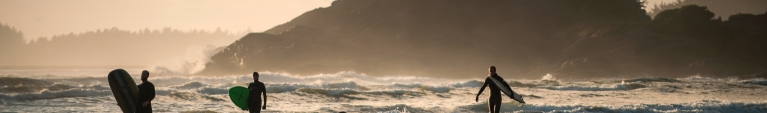 Surfers along the beach in Tofino, British Columbia